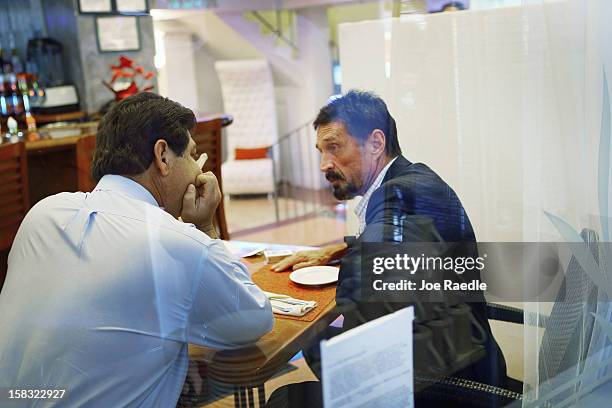 John McAfee talks to a member of the media as he sits down for breakfast at the Beacon Hotel where he is staying after arriving last night from...