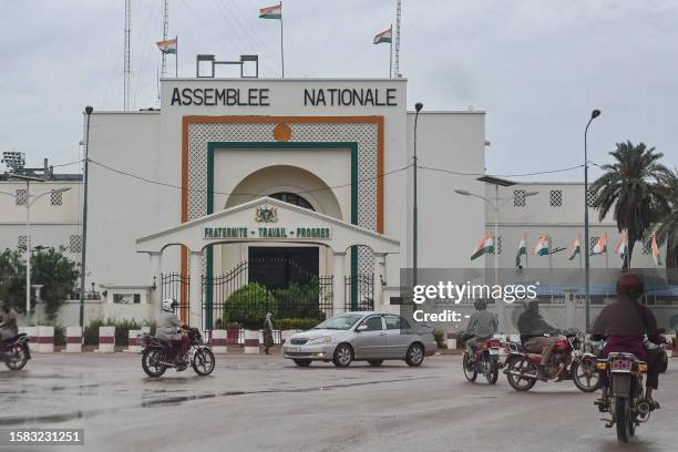 Motorists drive past the National Assembly in Niamey on August 7, 2023. Niger's military rulers were on Monday in defiance of an ultimatum to restore...