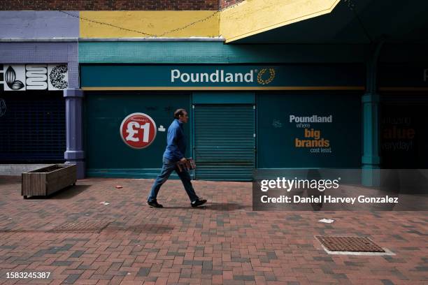 Member of the public walks past a closed down Poundland shop, a popular value bargain goods chain in the UK, as warnings come from retail and...