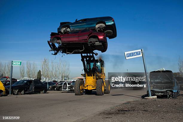 Front-loader moves scrapped automobiles past a Fiat SpA and a Skoda Auto AS sign in the yard of the Desguaces La Torre scrapyard in Madrid, Spain, on...