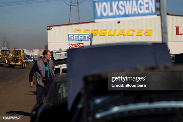 Customer searches for vehicle parts near signs for scrapped Seat, Volkswagen AG and PSA Peugeot Citroen automobiles in the yard of the Desguaces La...