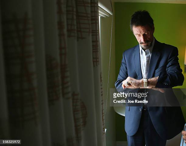 John McAfee checks his watch in his room at the Beacon Hotel where he is staying after arriving last night from Guatemala on December 13, 2012 in...