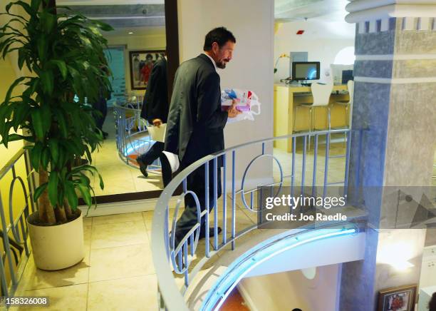 John McAfee walks to his room at the Beacon Hotel where he is staying after arriving last night from Guatemala on December 13, 2012 in Miami Beach,...