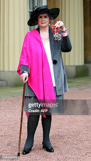 April Ashley, the first Briton to undergo sex-change surgery, poses with her Member of the British Empire medal following an Investiture ceremony at...