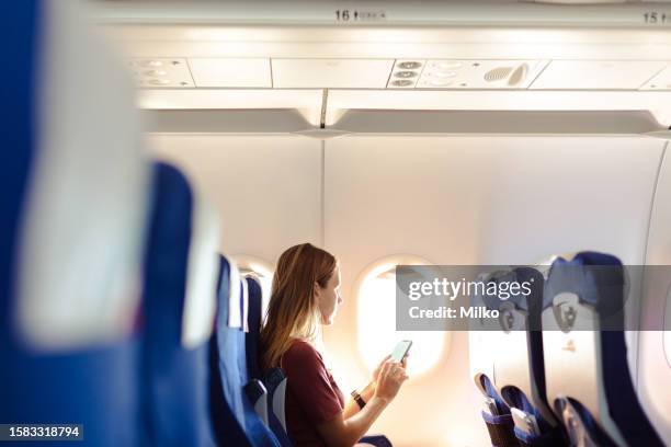 woman in the airplane holding smart phone with white screen - banco de avião imagens e fotografias de stock