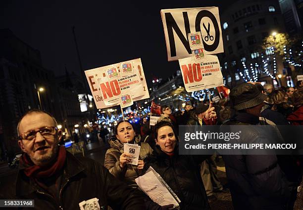 Demonstrators hold placards as they take part in a protest against government's austerity reforms and cuts in Madrid on December 13, 2012. Public...