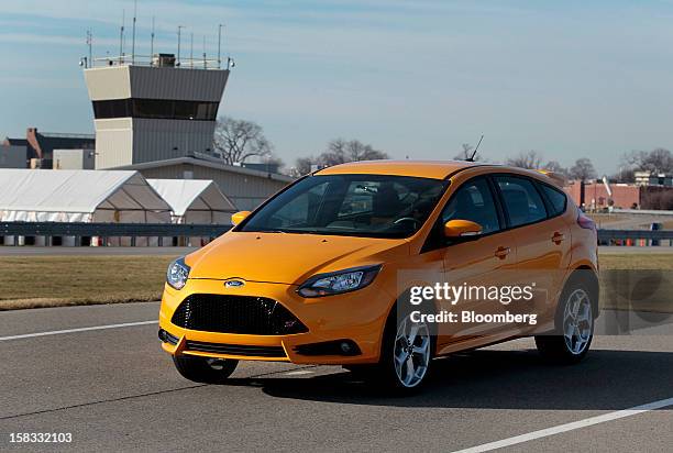 The 2013 Ford Motor Co. Focus ST vehicle in a color called "tangerine scream" sits parked on the test track at the company's Dearborn Development...