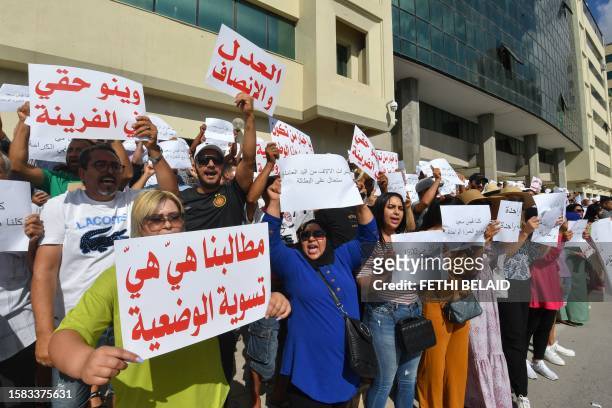 Demonstrators lift placards during a rally for bakery staff in front of the headquarters of the Ministry of Commerce in Tunis on August 7 following...