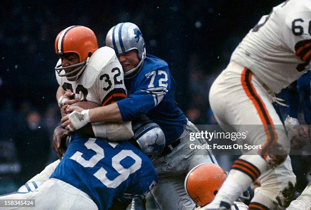 Jim Brown of the Cleveland Browns gets tackled by Ernie Clark and Floyd Peters of the Detroit Lions during an NFL football game December 8, 1963 at...