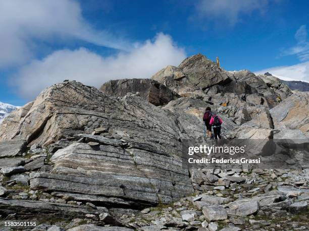 hikers climbing the steps to the golden statue of the holy virgin mary at monte moro alpine pass - mountain pass stock pictures, royalty-free photos & images