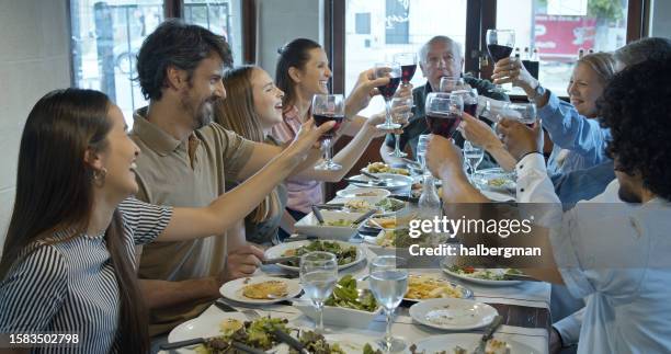 familia numerosa sonriendo y tintineando vasos juntos para un brindis - argentina steak fotografías e imágenes de stock