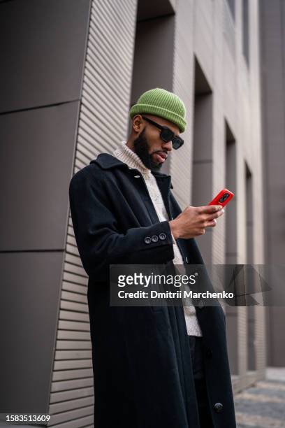 focused black hipster guy in sunglasses using smartphone, order taxi in online application - georgian man stock pictures, royalty-free photos & images
