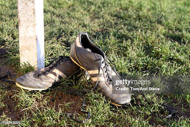 dirty football boots resting on a goal post - soccer boot stock pictures, royalty-free photos & images