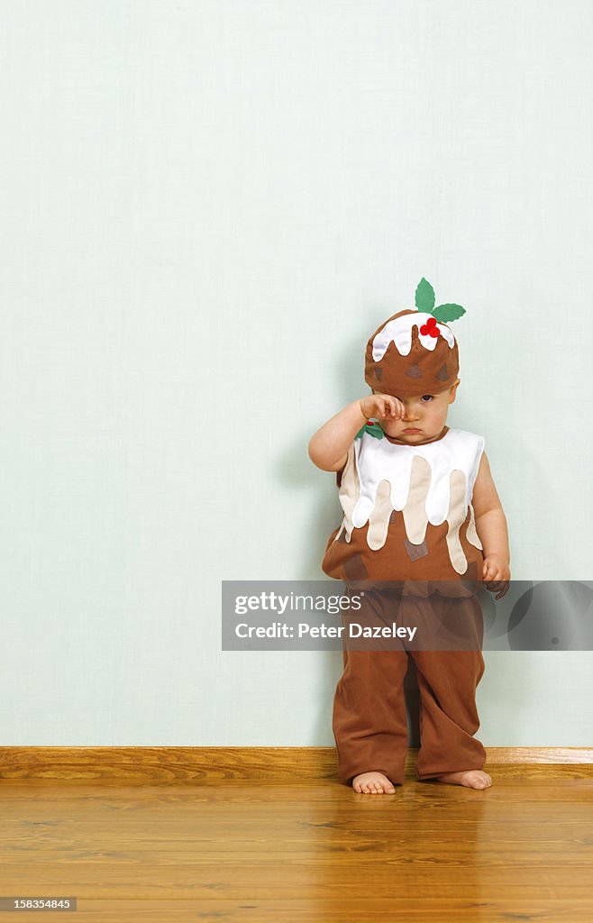 Unhappy baby boy in christmas pudding outfit