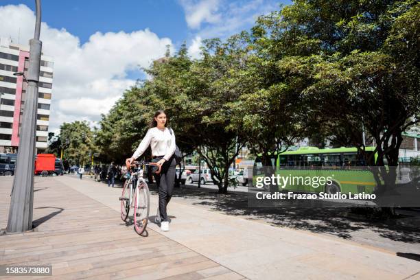 young woman walking while carry the bicycle in the city - bogota stockfoto's en -beelden