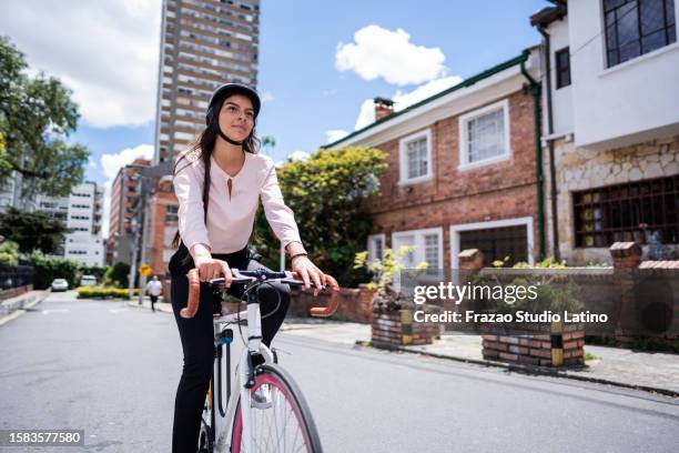 young woman cycling in the city - teenager cycling helmet stock pictures, royalty-free photos & images