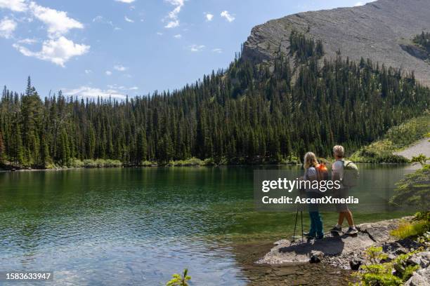senior couple explore alpine lake shoreline - montanhas rochosas canadianas imagens e fotografias de stock