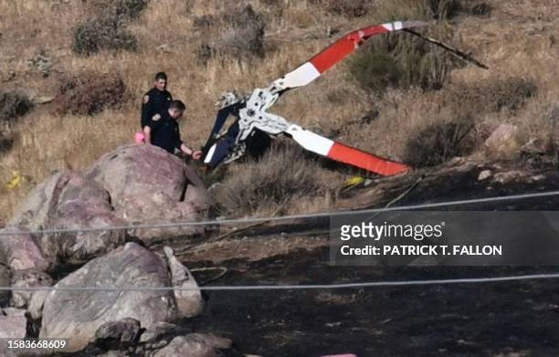 Investigators walk around rotor blades from one of the crashed helicopters on a burned hillside in Cabazon, California, on August 7, 2023. Three...