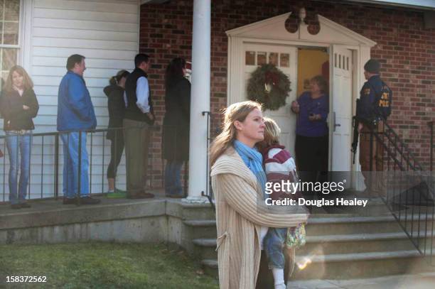 Woman holds a child as people line up to enter the Newtown Methodist Church near the the scene of an elementary school shooting on December 14, 2012...