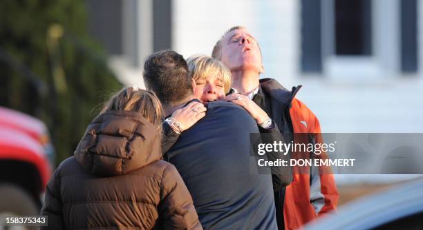 Unidentified people embrace on December 14, 2012 at the aftermath of a school shooting at a Connecticut elementary school that brought police...