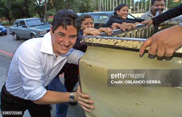 Oscar Almegor and many of his relatives push an old pick-up truck, 15 November 2002 in Guatemala City. Alemgor is the main character in the movie...
