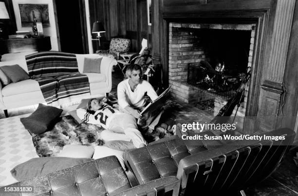 American fashion designer Ralph Lauren and his wife, therapist Ricky, read a newspaper beside the fireplace in their home, East Hampton, New York,...