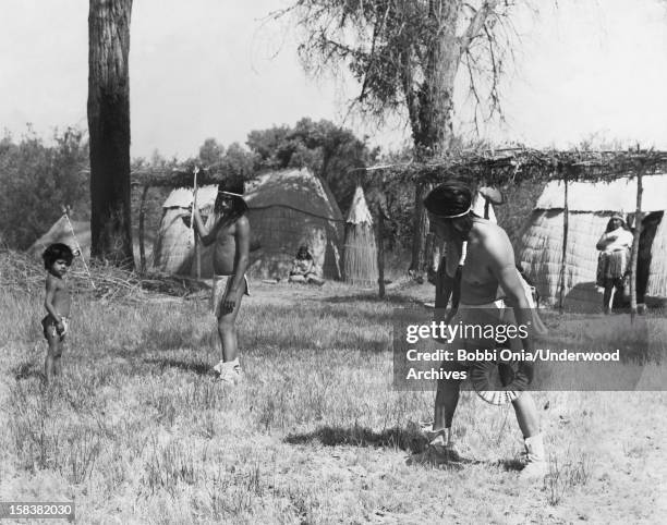 Native Americans play a hoop and pole game, California, late 1920s or early 1930s. The game involves throwing a spear through a rolling hoop of a...