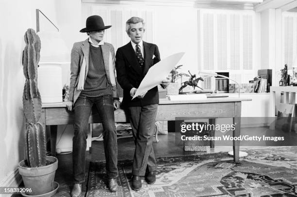 American fashion designer Ralph Lauren looks at drawings with an unidentified woman in his 7th Avenue office, New York New York, November 1977.