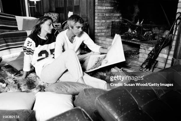 American fashion designer Ralph Lauren and his wife, therapist Ricky, read a newspaper beside the fireplace in their home, East Hampton, New York,...