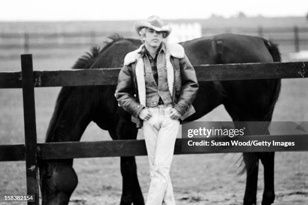 American fashion designer Ralph Lauren poses beside a horse near his home, East Hampton in November 1977.