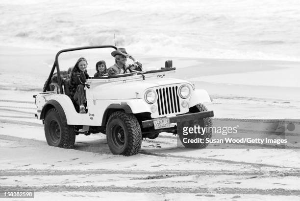 American fashion designer Ralph Lauren and his wife, therapist Ricky Lauren, drive in a jeep on the beach with their children, David, Andrew, &...