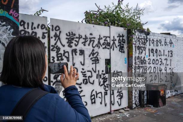 Woman films pro-democracy messages on an area of wall that had been graffitied with Chinese Communist Party ideology, on August 7, 2023 in Brick...