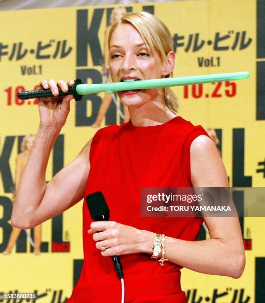 Actress Uma Thurman holds a toy sword in her mouth to show how to use it in her new film "Kill Bill" directed by Quentin Tarantino during a press...