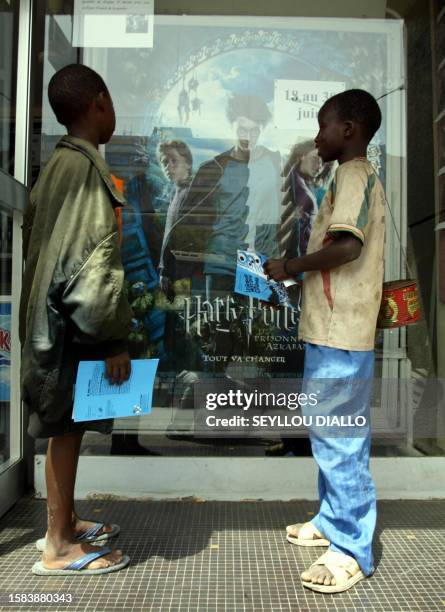Two young beggars look at Harry Potter's movie poster at Le Paris movie theater, at the Independence square 16 June 2004 in Dakar, during African...