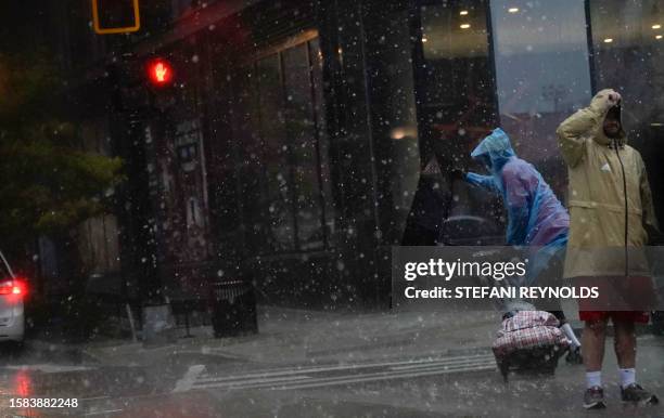 An umbrella is blown inside out as a person crosses the street during a storm in Washington, DC, on August 7, 2023. A tornado watch is in effect for...