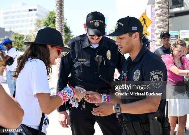 Concert-goer shows their friendship bracelets to Inglewood police officers at the Taylor Swift, The Eras Tour at SoFi Stadium on August 7, 2023 in...