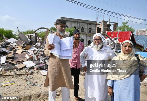 Abdul Rashid showing their property paper outside demolished shops in Nalhar village near Shaheed Hasan Khan Mewati Medical College after District...