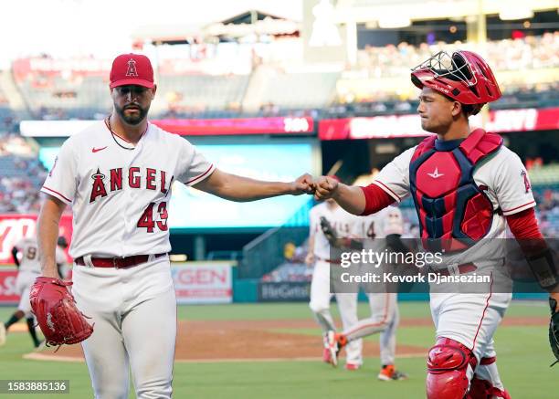 Starting pitcher Patrick Sandoval of the Los Angeles Angels fist bumps catcher Matt Thaiss after pitching out of a jam in the second inning against...