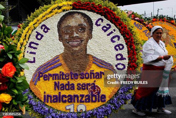 Farmer stands next to a flower arrangement known as "silleta" with an image of Colombian football star Linda Caicedo, currently playing the Australia...