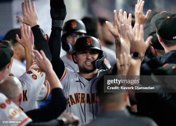 Davis of the San Francisco Giants is congratulated in the dugout after scoring on a double by Patrick Bailey during the ninth inning at Angel Stadium...