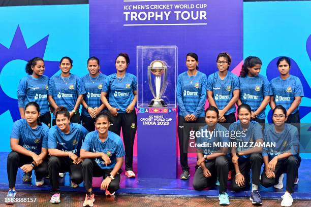 Bangladesh's women natoinal team members pose with the ICC Men's Cricket World Cup 2023 trophy at the Sher-e-Bangla National Cricket Stadium in Dhaka...