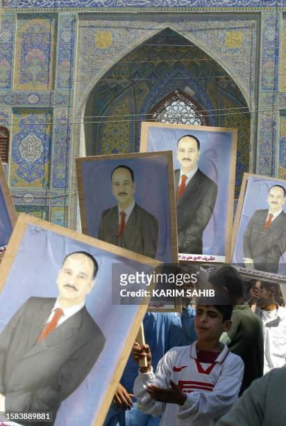 An Iraqi boy holds up pictures of Al-Sharif Ali bin al-Hussein, the son of a cousin of former Iraqi King Ghazi and pretender to the Iraqi throne,...