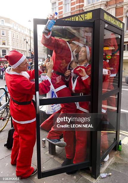 Revellers in Santa costumes jam into a telephone box during a 'Santacon' near Trafalgar Square in central London on December 15 less than two weeks...