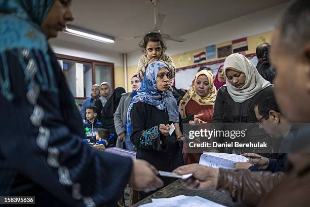 Woman carrying her daughter vents her frustrations to electoral staff as she and others wait to cast their vote during a referendum on the new...