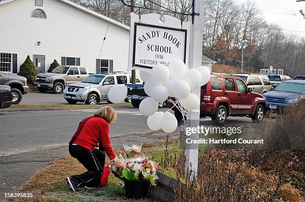 Woman places a memento at the sign for Sandy Hook Elementary School on Saturday, December 15 in Newtown, Connecticut, a day after a shooting rampage...