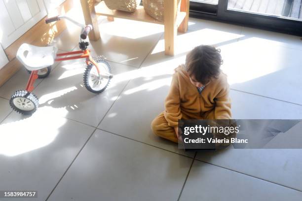 boy on kitchen floor playing with digital tablet - ipad blanc stock pictures, royalty-free photos & images