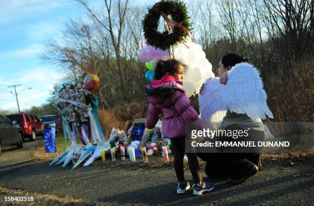 Young girl wearing angel wings arrives to offer her wings at a makeshift shrine to pay tribute to the victims of an elementary school shooting in...