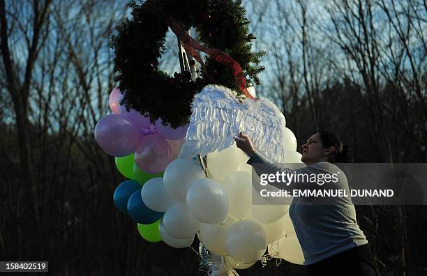 Mother hangs angel wings that her daughter was wearing at a makeshift shrine to pay tribute to the victims of an elementary school shooting in...