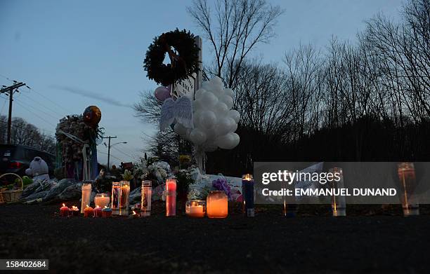 Candles burn at a makeshift shrine to pay tribute to the victims of an elementary school shooting in Newtown, Connecticut, on December 15, 2012. A...