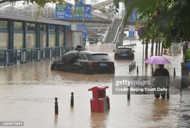 Man wades through flooded road on July 31, 2023 in Beijing, China. Beijing maintained red alert on July 31 as heavy rains continue to hit the city.